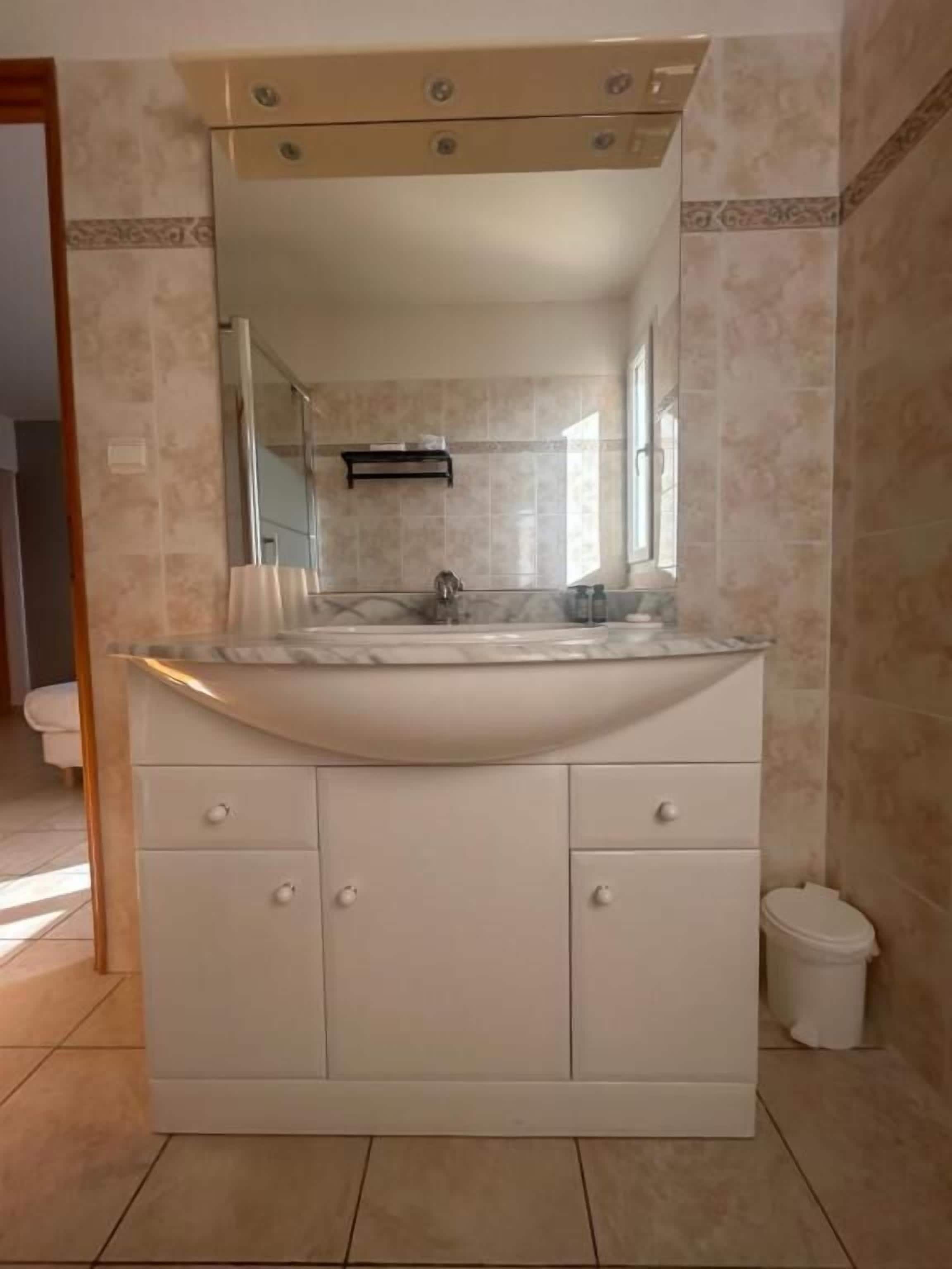 Un baño con un tocador amplio, un espejo y un inodoro.