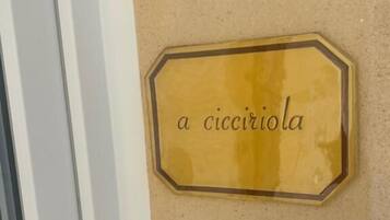 Una placa hexagonal con el texto 'a cicciola' sobre una pared color beige.