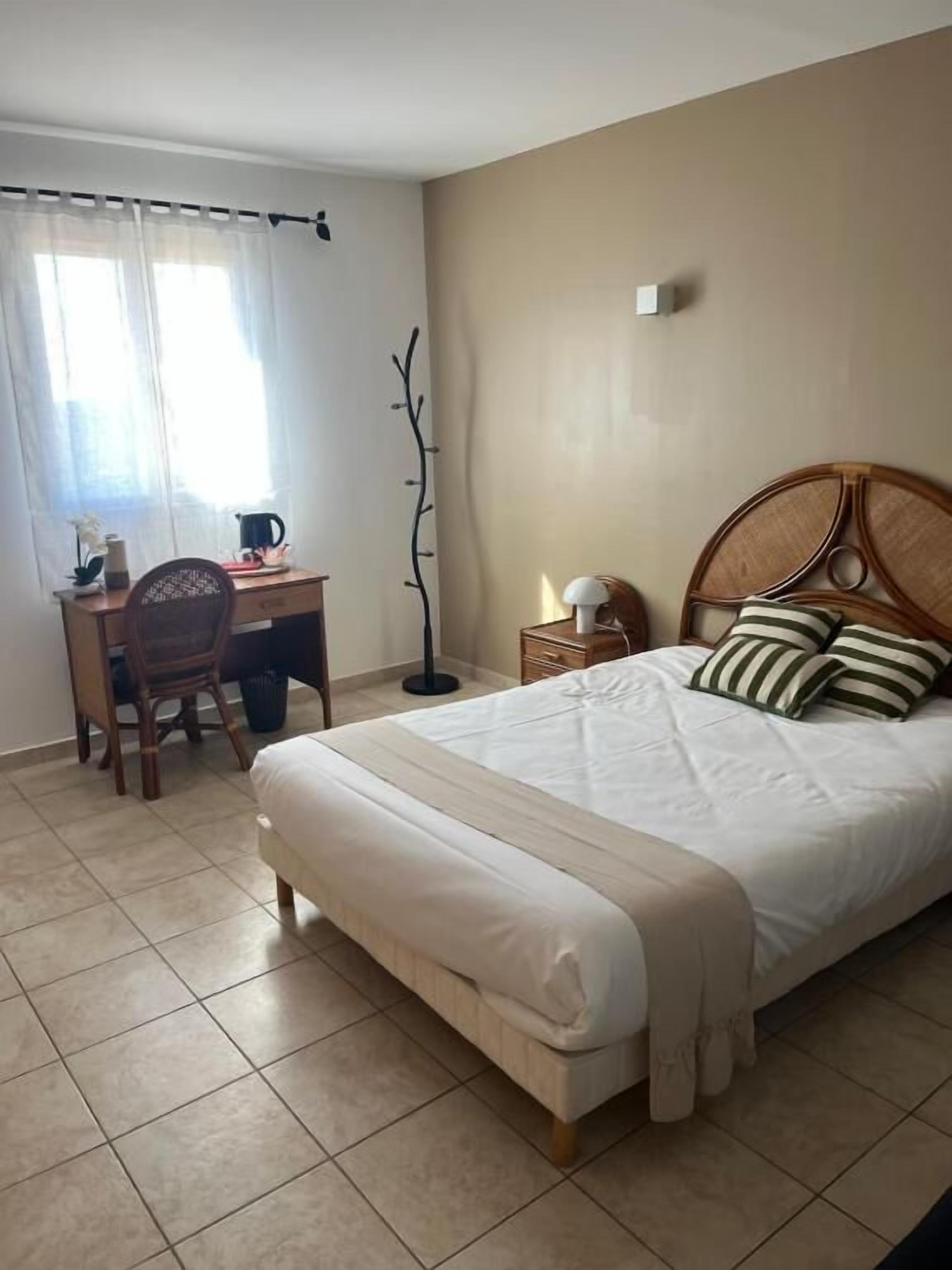 Un dormitorio con cama, escritorio, silla y lámpara.