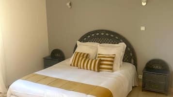 Quarto com uma cama, duas mesas de cabeceira e uma luminária fixada na parede.
