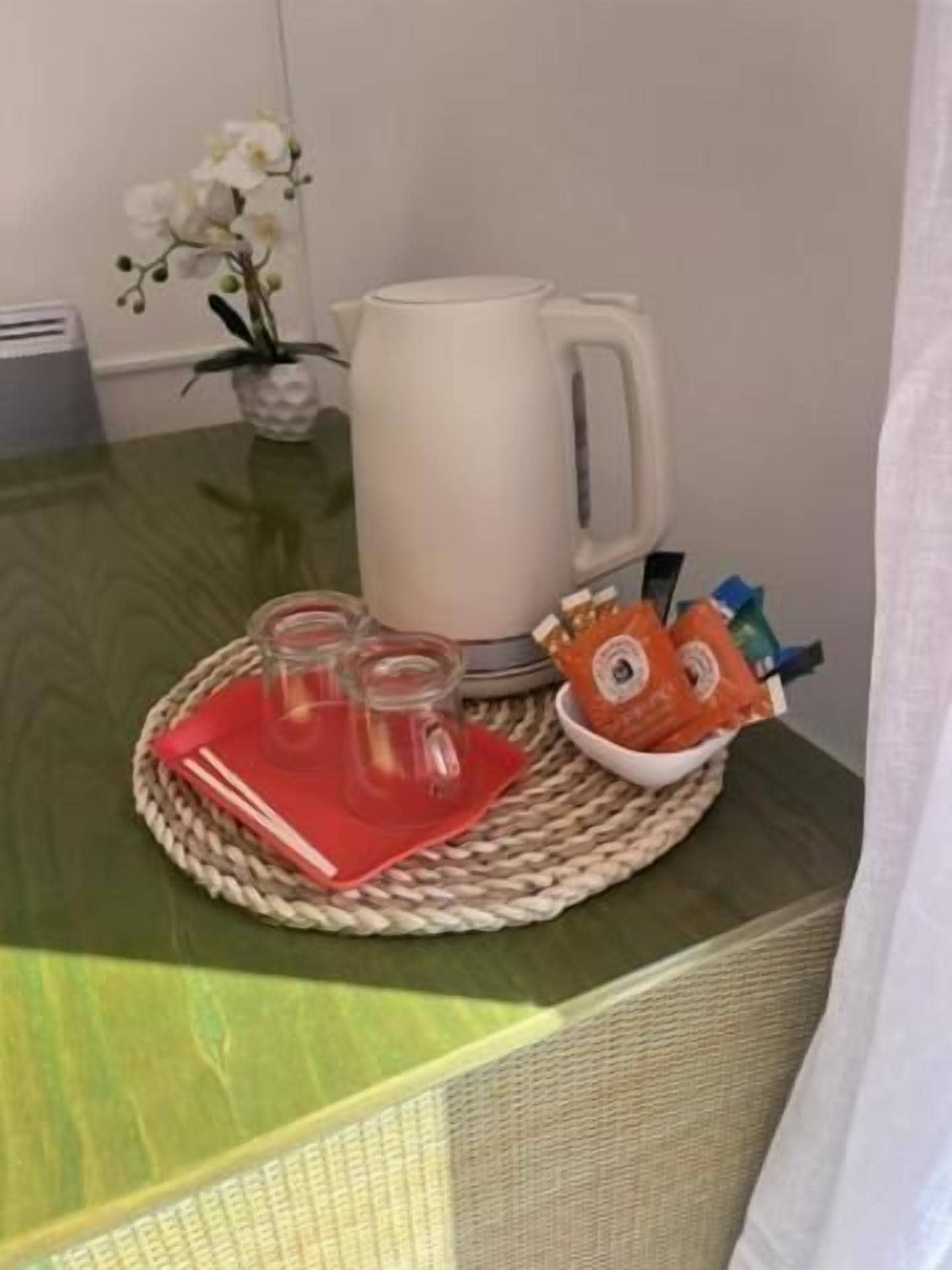Una mesa con una taza blanca, tres vasos y una pequeña cesta de aperitivos.