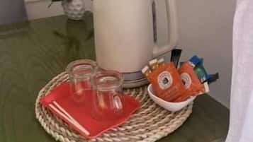 Una mesa con una taza blanca, tres vasos y una pequeña cesta de aperitivos.