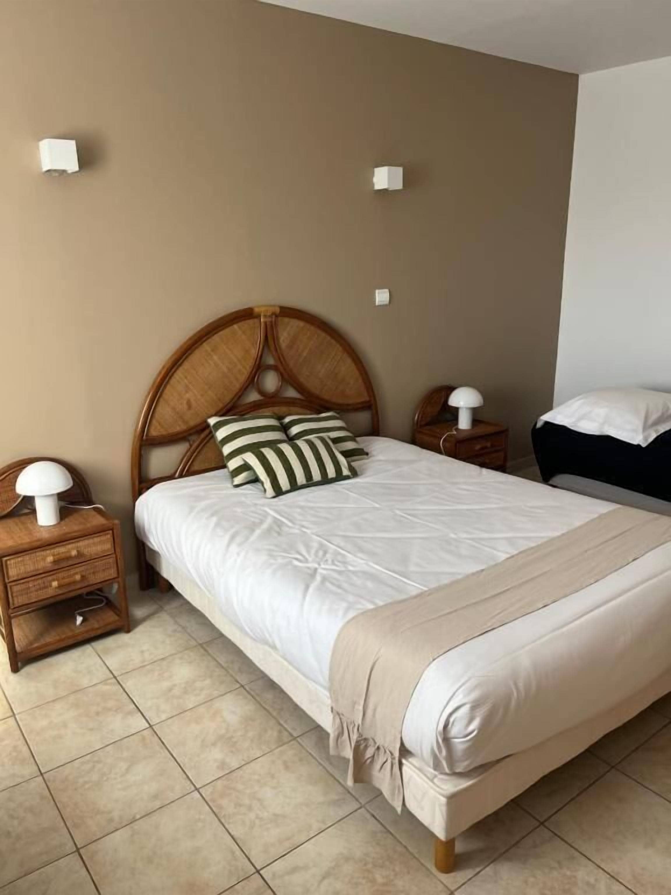 A bedroom with a single bed, two bedside tables, and a headboard.