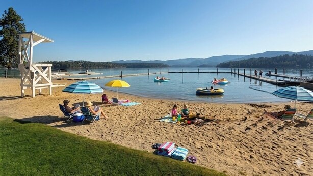 Ein Strand mit Liegestühlen, Sonnenschirmen und einem Rettungsturm.