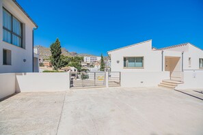 A residential area with a gated entrance, a building with a balcony, and a clear blue sky.