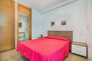 A bedroom with a bed, a nightstand, a dresser, a shower, and a door. - Beachside Home with Shared Pool, Cala Molins (Cala Sant Vicenç)