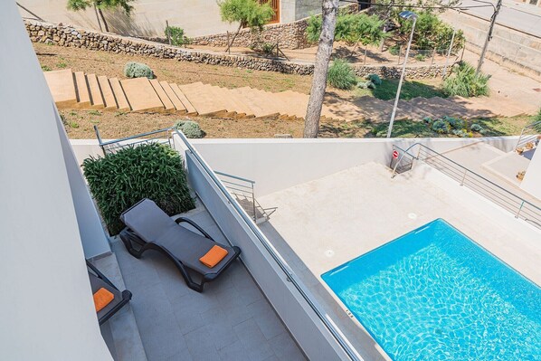 Un espace piscine aménagé sur le toit, avec deux chaises longues et un petit jardin.