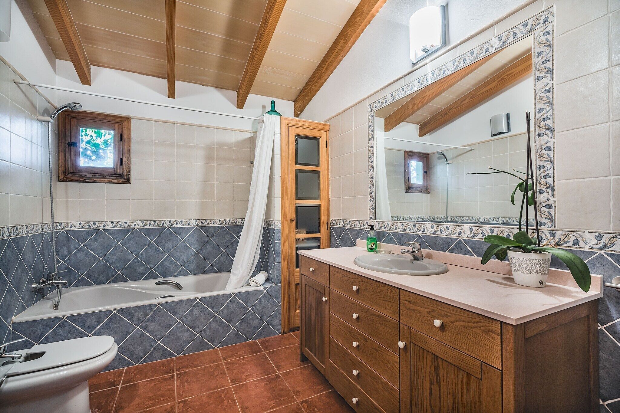 A bathroom with a bathtub, a shower, a toilet, and a vanity with a mirror.