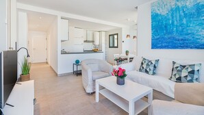 A modern living room with a sofa, coffee table, and a painting on the wall. - Apartment 20 m from Cala Molins Beach (Cala Sant Vicenç)