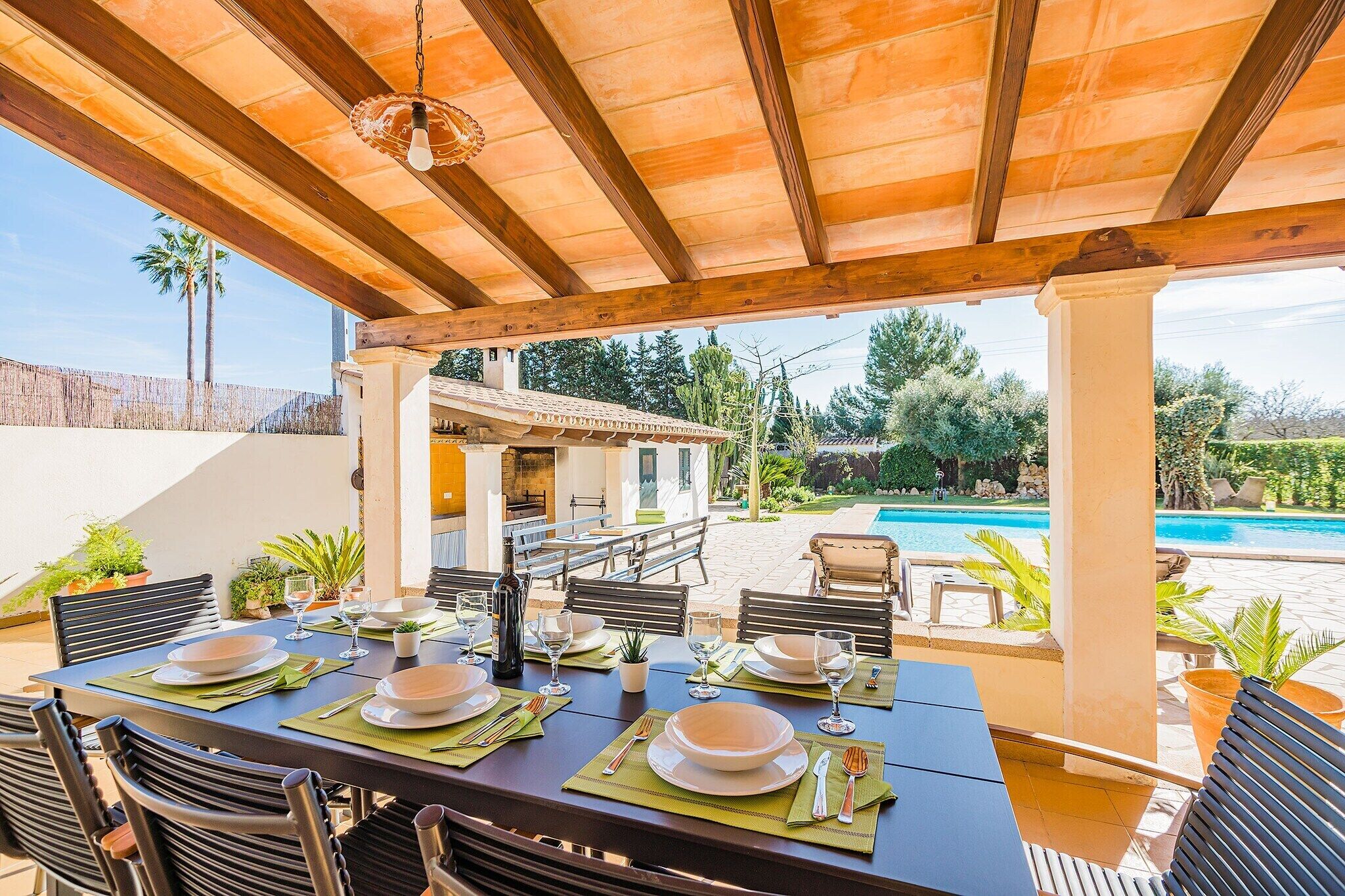 Un espace de restauration en plein air, avec des tables dressées pour le repas, donnant sur une piscine et un jardin.