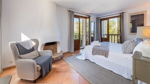 A bedroom with a sofa, a bed, a fireplace, and a view of the outdoors. - Elegant Villa witj Heated Pool, Pollença (Pollensa / Pollença)