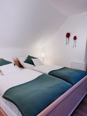 A double bed with green and white bedding, a bedside table with a lamp, and two red flower decorations on the wall. - Spacious Vacation Rental in the Upper Black Forest with an Infrared Sauna & South-Facing Balcony (Sankt Blasien)