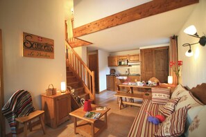 Ein gemütliches Wohnzimmer mit Holztreppe, einer Essecke und einer Küche.