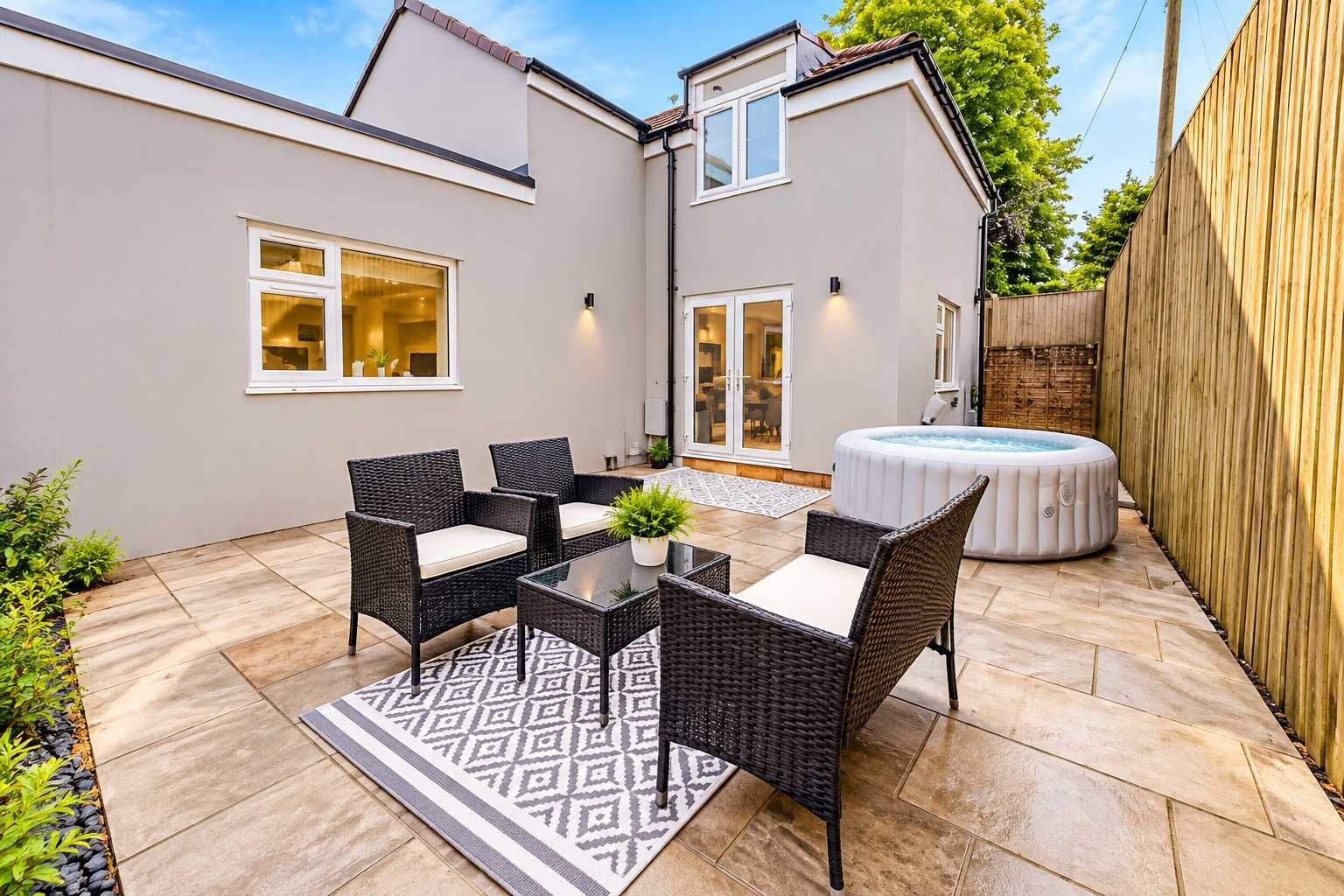 Eine Terrasse mit Korbmöbeln, einem Whirlpool und einem gemusterten Teppich.