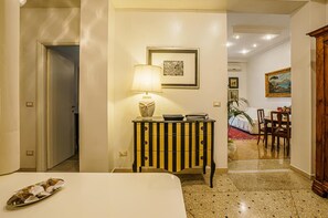 A hotel room with a bed, a bedside table with a lamp, a small cabinet, and a dining area with a table and chairs. - 'Casa Riz Vaticano' Apartment with Balcony, Wi-Fi & Air Conditioning (Rome)