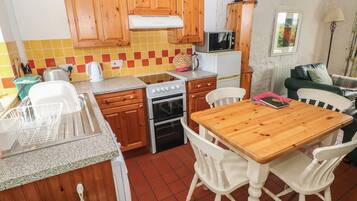 Una cocina compacta con armarios de madera, microondas, estufa y una mesa de comedor con sillas.