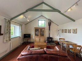 Una sala de estar acogedora con techo inclinado, chimenea, televisor, sofá y mesa de comedor.