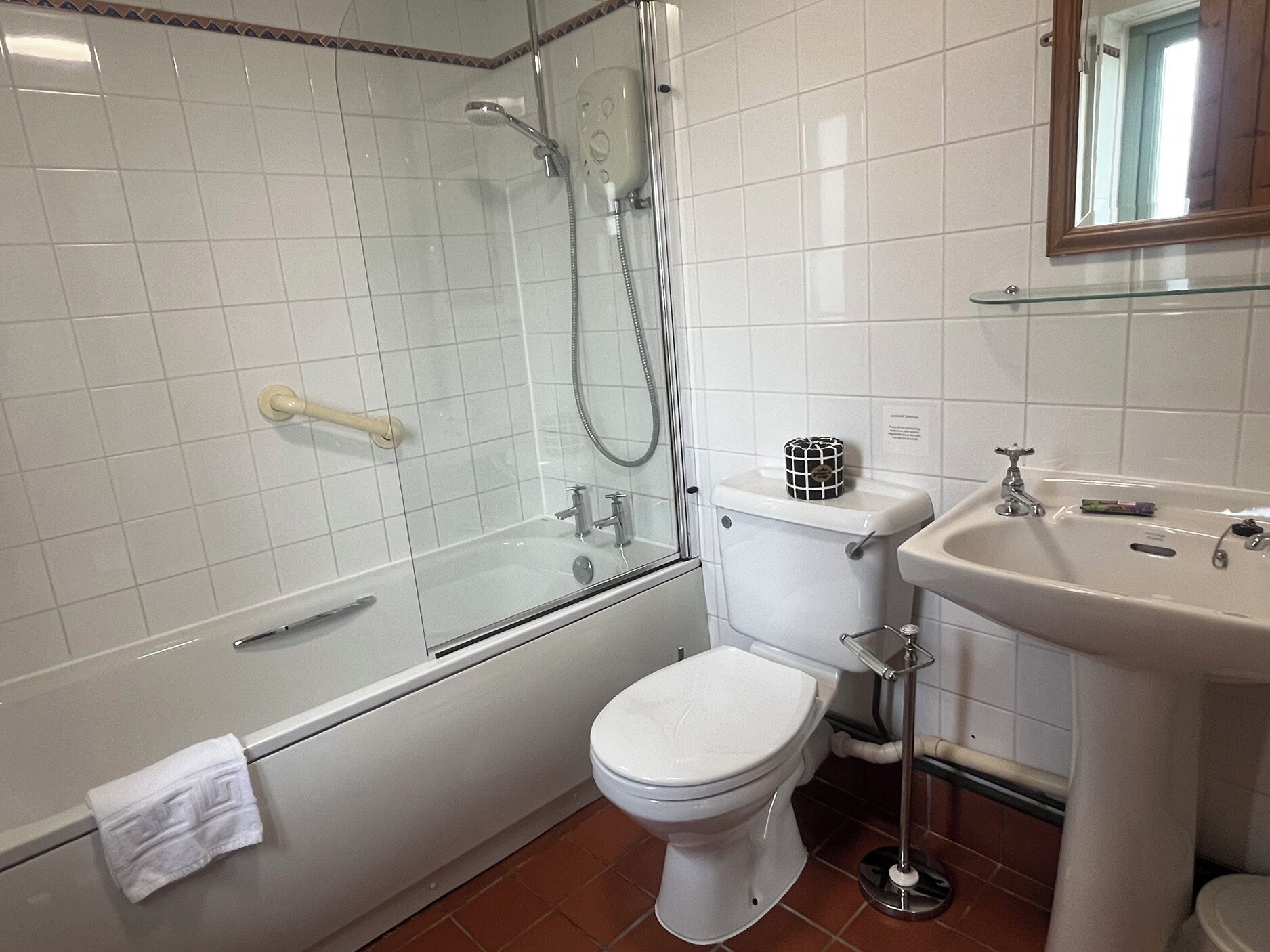 A bathroom with a glass-enclosed shower, a toilet, and a sink.