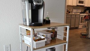 A kitchen area with a coffee maker on a cart, a microwave, and cabinets. - Family-Friendly Houston Home (Houston)