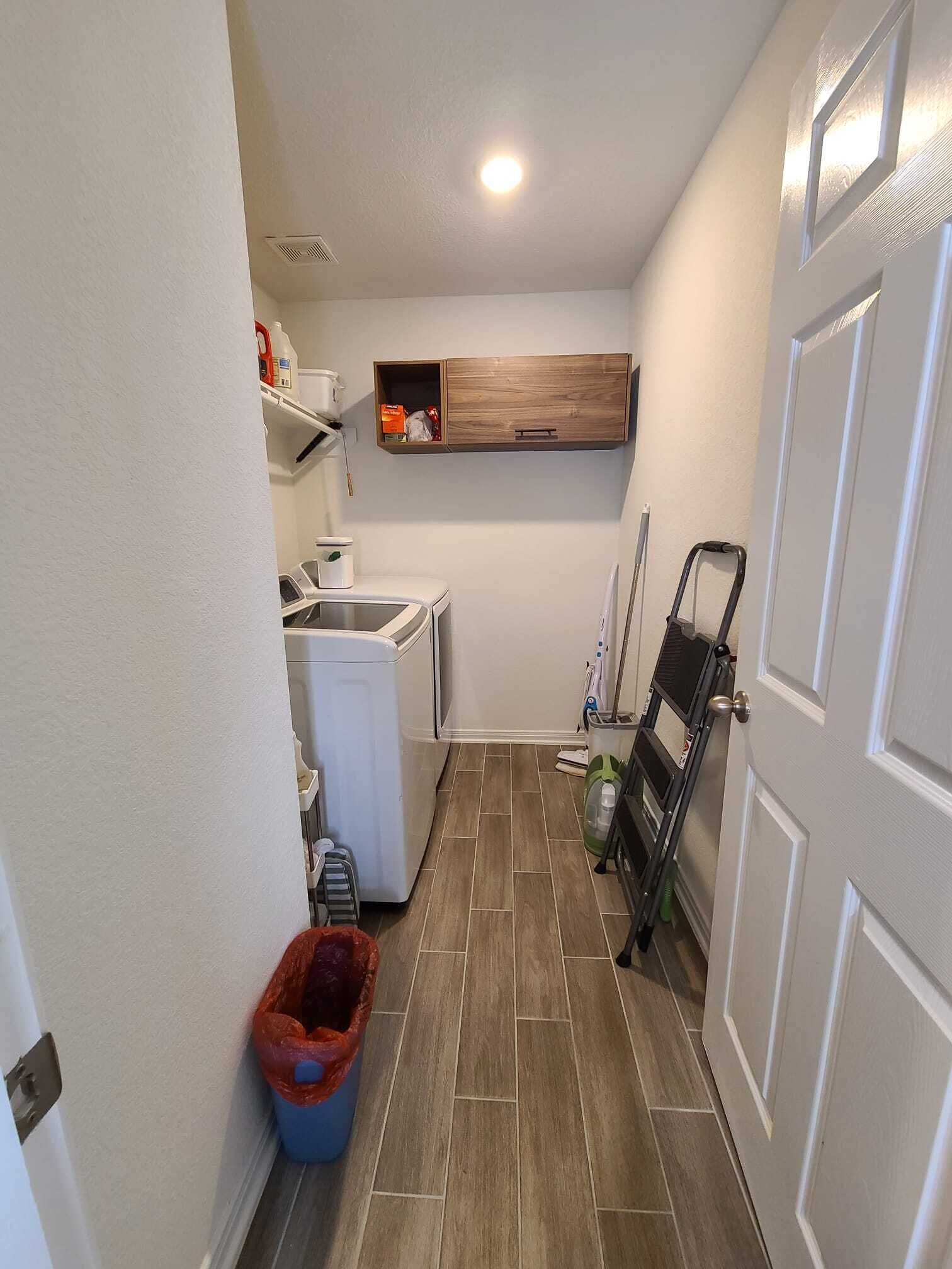 A laundry room with a washing machine, a drying rack, and a shelf with cleaning supplies.