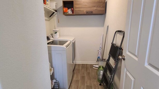 A laundry room with a washing machine, a drying rack, and a shelf with cleaning supplies. - Family-Friendly Houston Home (Houston)