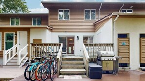 Un bâtiment à deux étages doté d’un porche abrité, d’un barbecue et de vélos garés à l’extérieur.
