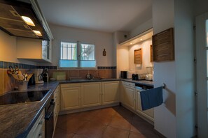 A kitchen with a stove, sink, and cabinets. - House for 11 people with a 14-meter pool and large yard (La Boissière)