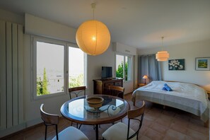 A hotel room with a bed, a TV, a dining table with chairs, and large windows. - House for 11 people with a 14-meter pool and large yard (La Boissière)