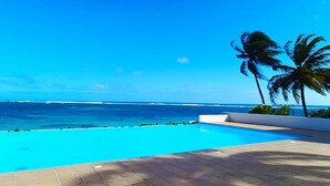 Cielo azul despejado, una piscina y vista al océano.