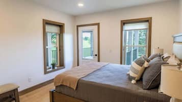 A bedroom with a bed, a bench, a lamp, and three windows.