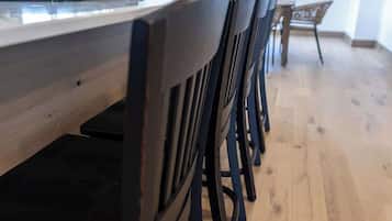 A modern kitchen with a long counter and black chairs.