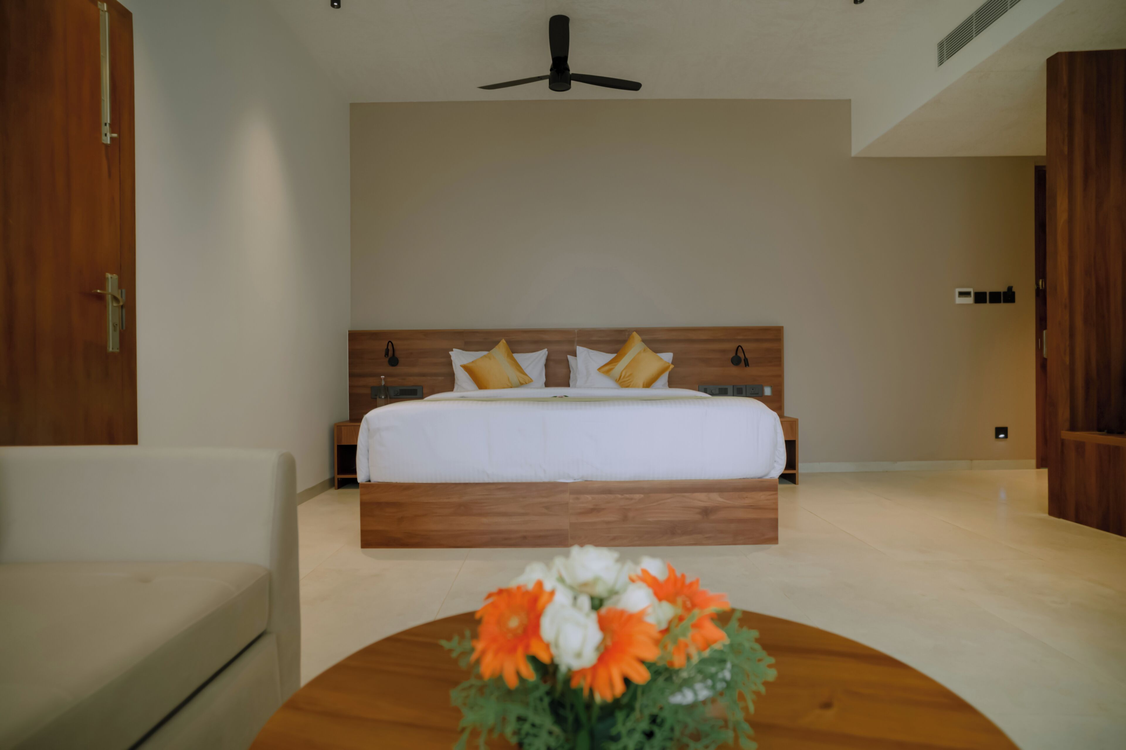 Une chambre à coucher avec un lit, des tables de chevet, un ventilateur de plafond et un plancher en bois.