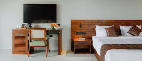 Una habitación de hotel con una cama, un escritorio con una silla, un televisor y una mesita de noche.