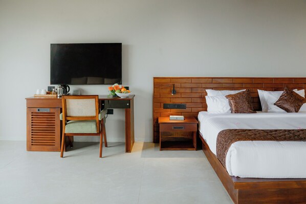 A hotel room with a bed, a desk with a chair, a television, and a nightstand. - Mountree Munnar by Kondody Hotels (Devikolam)