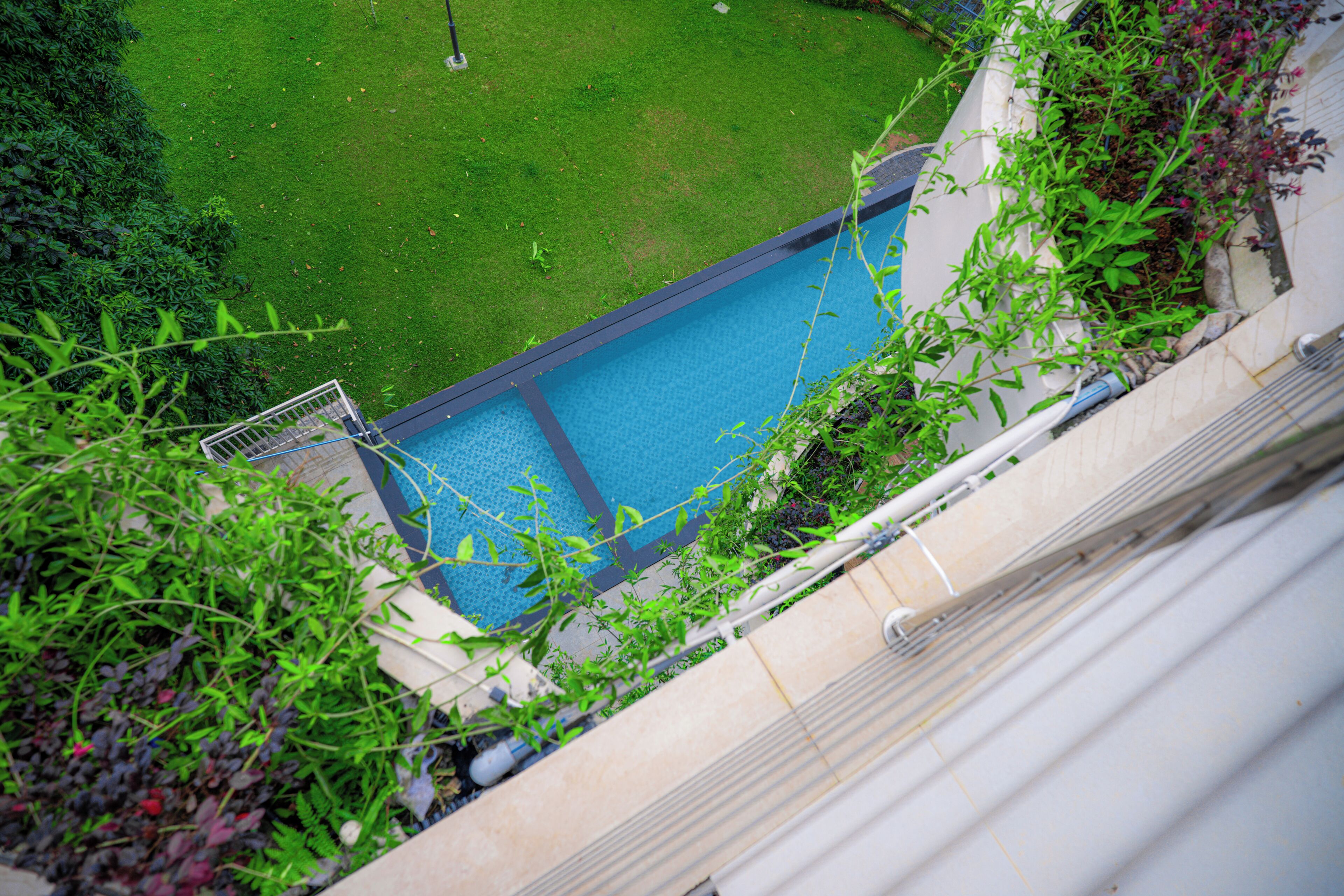 A swimming pool with a clear view of the surrounding grassy area and a building structure.