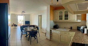 Una cocina con comedor, pileta, alacenas y microondas.