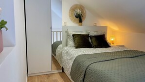 Ein Schlafzimmer mit Bett, Nachttisch, Lampe und einem Wandspiegel.