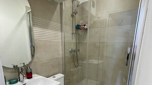 Ein modernes Badezimmer mit einer Duschkabine, einem weißen Waschbecken und einer Toilette.