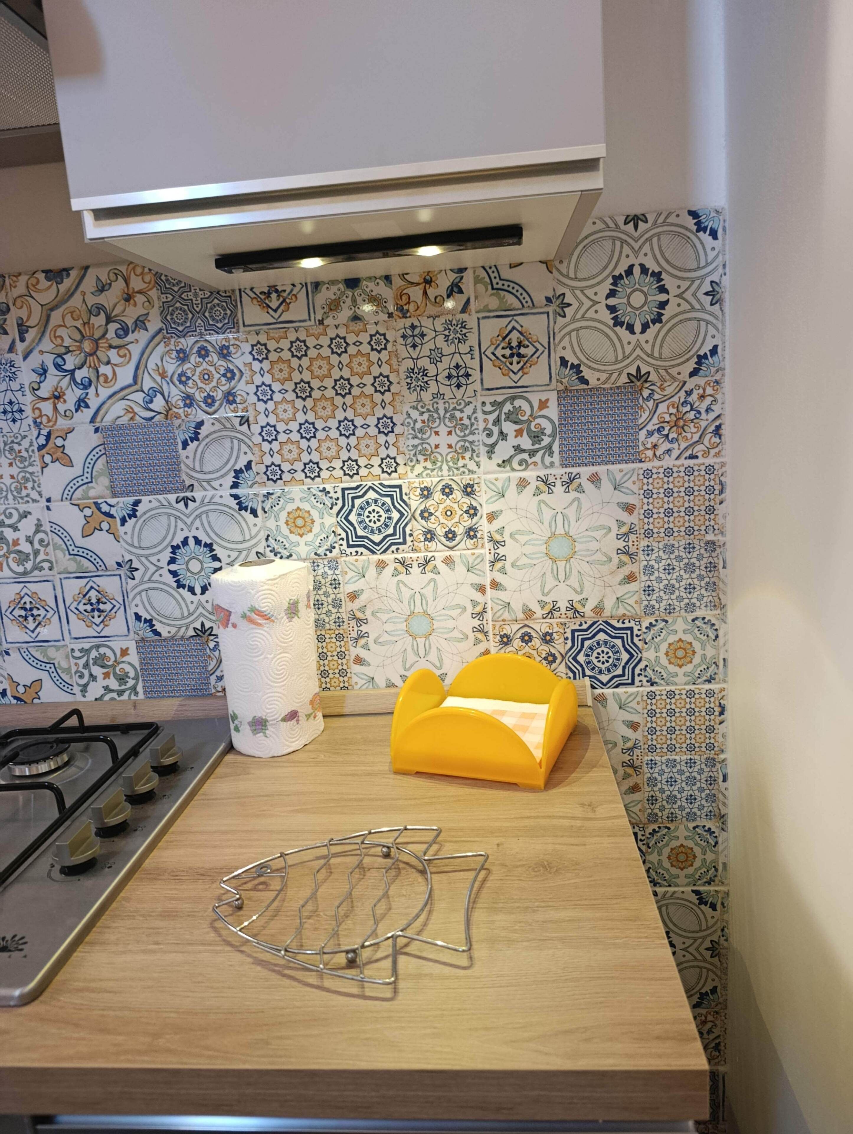 A kitchen with a patterned tile backsplash, a gas stove, and a yellow towel holder.