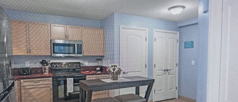 A kitchen with wooden cabinets, a microwave, an oven, and a dining table with chairs.