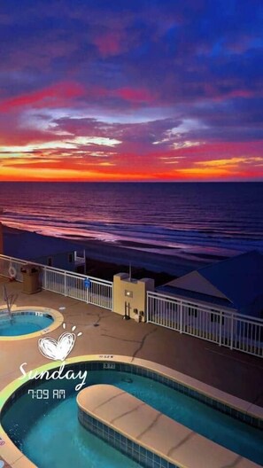 A pool area with a sunset view, a pool with a heart-shaped design, and a timestamp indicating 7:09 AM. - Prince Resort |Ocean View| King Bed | Pools & Lazy River (North Myrtle Beach)