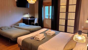 A hotel room with two beds, a desk, a TV, and a window with curtains.