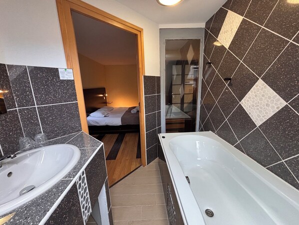 A bathroom with a bathtub, two sinks, and a shower area.