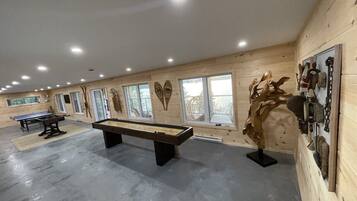 A spacious room with a pool table, a billiards table, and a wooden sculpture.