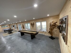 Una habitación amplia con mesa de billar, una mesa de futbolín y una escultura de madera.