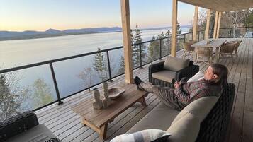 A covered outdoor seating area with a view of a body of water and distant mountains.
