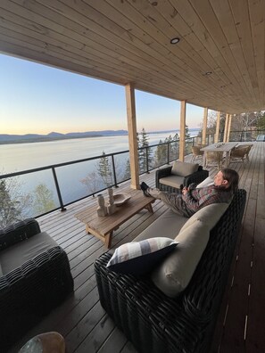 Un espacio de estar al aire libre cubierto con vista a un cuerpo de agua y montañas distantes.