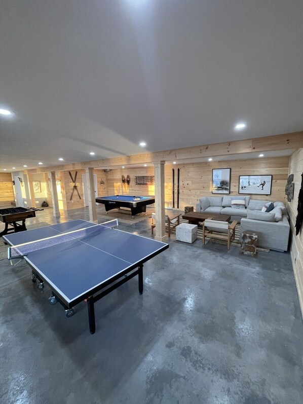 Una habitación con mesa de ping pong, mesa de billar y un sofá.
