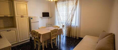 A compact living space with a kitchenette, a dining area, and a sofa.