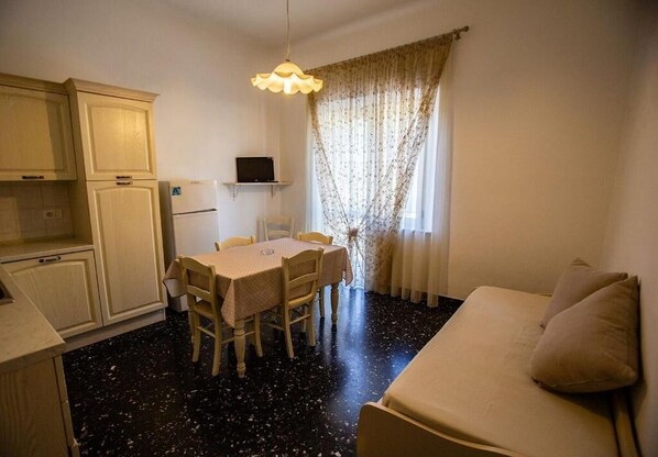 A compact living space with a kitchenette, a dining area, and a sofa.